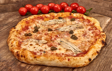 Homemade fresh delicious gourmet pizza Romana whit anchovies,capers and oregano,Tasty italian pizza isolated on wooden table, close up