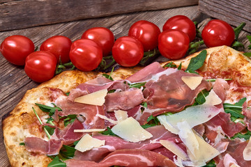 Homemade fresh delicious gourmet pizza whit grana cheese, raw ham and rocket ,Tasty italian pizza isolated on wooden table,Close up with selective focus