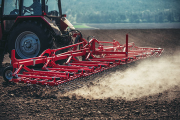 Wall Mural - Farmer with tractor seeding crops at field