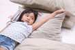 © kornnphoto - Asian children cute or kid fashion girl wake up in morning or sleeping and open eye with smile and raise arm or armpit show on white bed with brown pillow and bedtime in bedroom at home or hotel