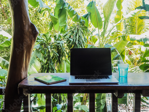 Cuadros en Lienzo laptop of a digital nomad on a wooden table in nature with a green tropical back