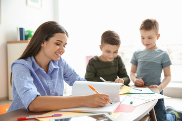 Wall Mural - Cute little children with teacher in classroom at school