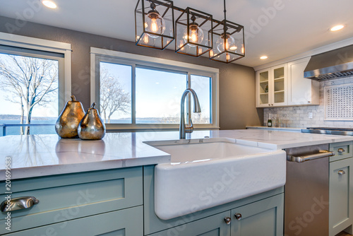Fotografía Beautiful kitchen room with green island and farm sink.