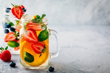 Wall Mural - Infused detox water with orange, strawberry, blueberry and mint. Ice cold summer cocktail or lemonade.