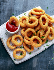 Wall Mural - Fried Onion Rings with Ketchup on white cutting board.