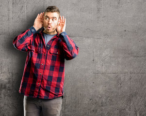 Sticker - Young handsome man holding hand near ear trying to listen to interesting news expressing communication concept and gossip