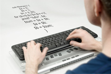 Blurred man in the foreground writing on keyboard, hands are on the move, a example of programming in the programming language: 