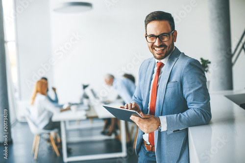 Young businessman with digital tablet in office Poster Mural XXL