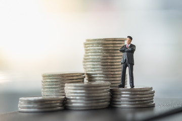 Business, Money and planning concept. Businessman miniature figure standing on stack of silver coins.