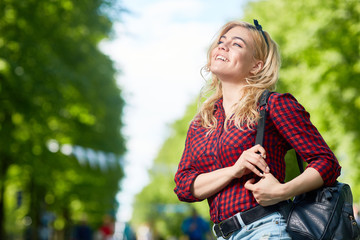 Wall Mural - Happy restful girl with backpack looking at one of amusements while taking walk in one of modern theme parks