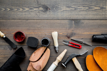 Wall Mural - Tools for shoe repair. Hummer, awl, knife, sciccors, wooden shoe, insole, paint and leather. Dark wooden background top view copy space