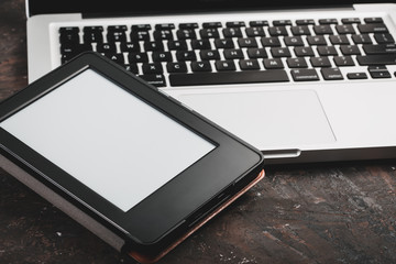 E-book and paper books on the table with a cup of coffee, a laptop and reading glasses. Concepts of self-education.