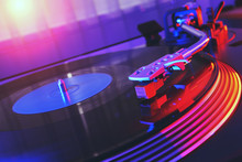 Turntable Vinyl Record Player On The Background Of A Sunset Over The Lights City. Sound Technology For DJ To Mix & Play Music. Black Vinyl Record. Needle On A Vinyl Record