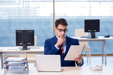 Young handsome businessman employee working in office at desk