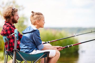 Wall Mural - Father and son with rods fishing together by lake on summer weekend