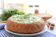 Bread loaf filled with tasty spinach sauce on table