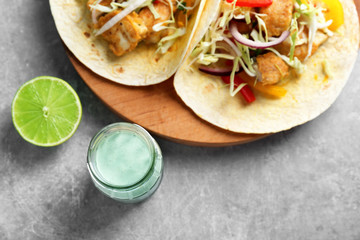 Wall Mural - Tasty creamy lime sauce for fish taco in glass jar on table