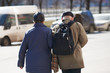 Back view of senior couple taking a walk in a street. She is holding his hand.