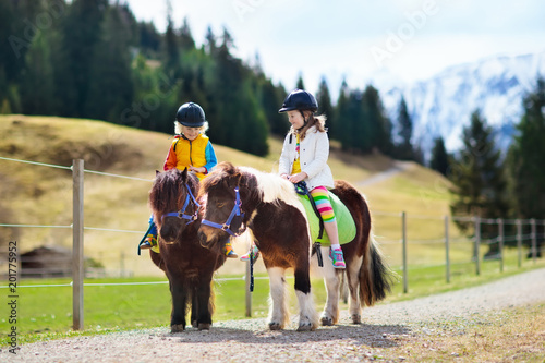 Cuadros en Lienzo Kids riding pony. Child on horse in Alps mountains
