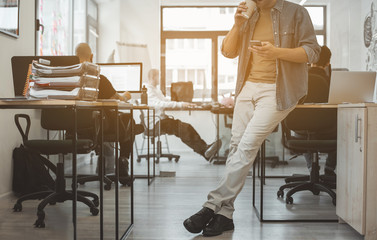 Poster - Male typing in cellphone while tasting mug of delicious beverage in modern office. Employer during break concept