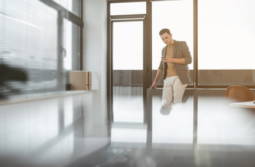 Poster - Portrait of concentrated male typing in phone while standing in office. Focused employer using gadget concept. Copy space
