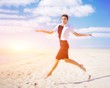 © raisondtre - Fashion shot on the coast. Beautiful sexy woman in a black dress and a white blouse. Young relaxed girl dancing barefoot, jumping high on sandy beach.