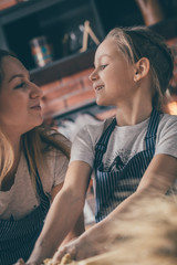 Canvas Print - Mother and daughter looking at each other while cooking on kitchen together. 