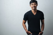 Smiling asian guy in black blank t-shirt, grunge wall, studio portrait
