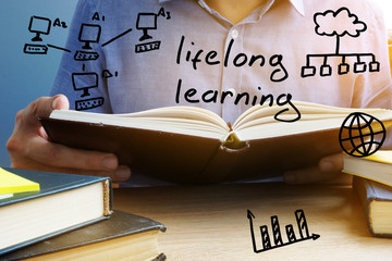 Wall Mural - Lifelong learning concept. Man holding and reading the book.