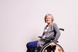 Portrait of a senior woman with wheelchair in studio.