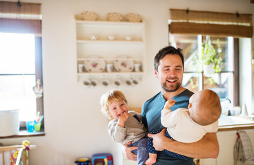 Wall Mural - Father with two toddlers at home.