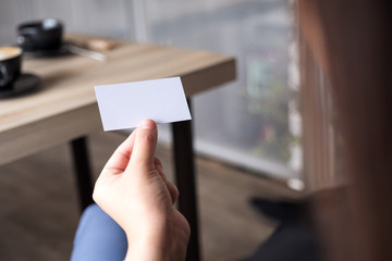 Businesswoman holding an empty business card while sitting in office