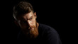© USM Photography - Portrait of young handsome bearded man looking forward Studio shot over black background.