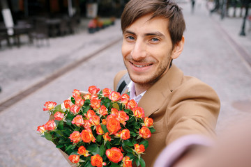 Smiling man making selfie with flowers