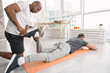 © zinkevych - Physical therapy. Serious nice man looking at the patients leg while being responsible for the physical therapy