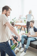 © LIGHTFIELD STUDIOS - side view of smiling young man opening beer bottle by corkscrew and friends sitting near
