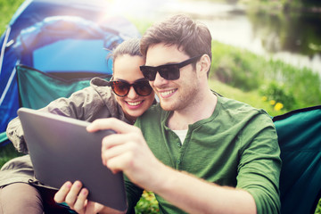 Sticker - travel, hiking, technology, tourism and people concept - smiling couple with tablet pc computer sitting on chairs at camping tent