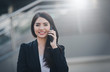 © nuttawutnuy - Portrait of business woman happy smile talking on smartphone with blurred background. Business concept. Vintange tone