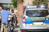 Fototapeta  - Samochód ochrony wśród ludzi z rowerami w mieście.