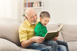 © Prostock-studio - Senior man reading book for his grandchild