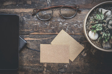 Mock-up of two blank craft business cards, smartphone, eye glasses, headphones on natural brown authentic wooden desk. Business empty mock-up background for message writing.Creative work concept