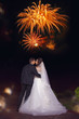 Romantic kiss of newlyweds on background of beautiful fireworks