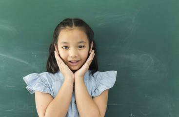 Surprised little Asian girl or funny child girl with hands close to face smiling looking at camera on green background with copy space. lifestyle,happy and kids concept