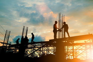 silhouette of engineer and construction team working at site over blurred background sunset pastel f