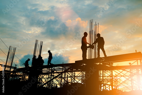 Fotomural Silhouette of engineer and construction team working at site over blurred background sunset pastel for industry background with Light fair