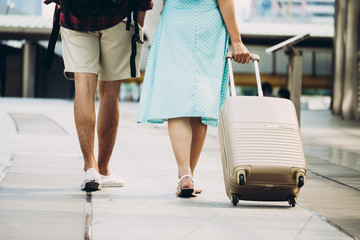  Close up of Couple travelers with luggage wakling on city street. Vacation and travel concept