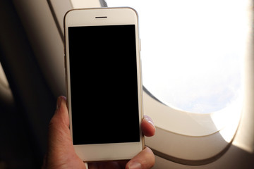 Poster - Hand holding mockup smartphone with plane window background