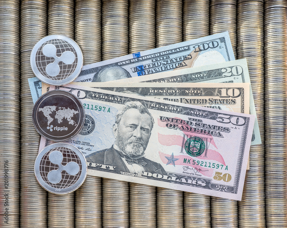 Silver crypto coins Ripple XRP, paper notes us dollars. Metal coins are laid out in a smooth background to each other, close-up view from top, crypto currency exchange of money.