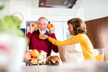 Poster - Senior couple unpacking food in the kitchen, having fun.