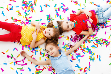 happy children on holidays  jumping in multicolored confetti on white